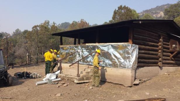 Firefighters wrap Noonday cabin with fire protection. (Courtesy inciweb)